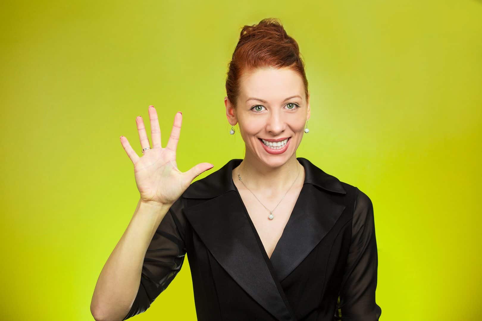 Closeup portrait, happy, smiling young woman making five times sign gesture with hand fingers, isolated green background. Positive human emotion facial expression feelings, attitude, symbol, reaction